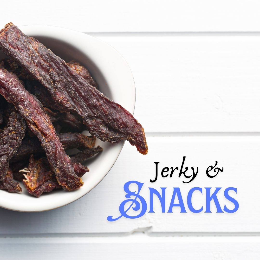 Jerky and snacks collection with dried beef jerky strips in a white bowl on rustic white wooden background.