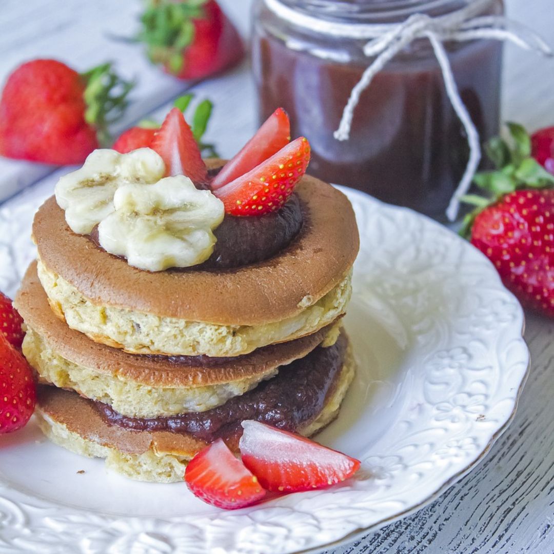 pancakes with strawberries and bananas on top on a plate