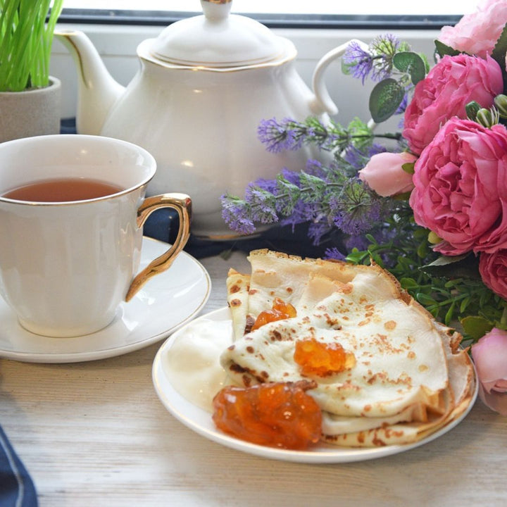 peach preserves with pancakes on a plate with a cup of coffee