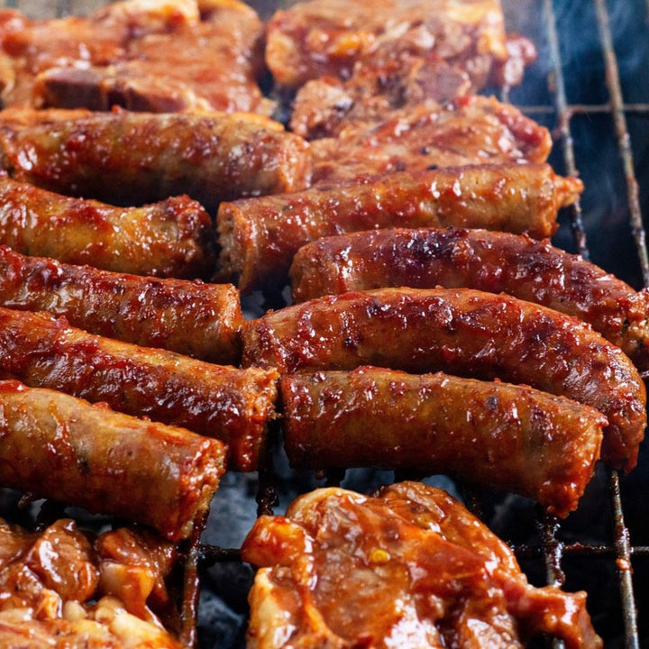 grilled pork chops and sausge links with bbq sauce on them.