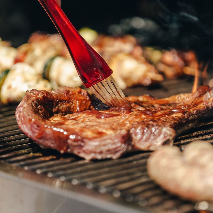 brushing bbq sauce on a grilled steak